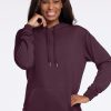 A person smiling while wearing a Wine Tasting Avery Hoodie from Woolx, with their right hand touching their chin. The dark purple merino wool hoodie features a large front pocket and drawstrings, offering both comfort and style against the plain white background. | Keesha is 5'9.5", wearing a size S