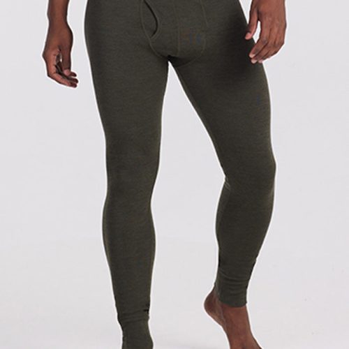 A person wearing the Woolx Backcountry Leggings in Dark Moss, designed for cold weather adventures. The waistband is black with the brand name "Woolx" repeated in gray. The individual, clad in this Merino wool base layer, stands against a plain background with hands relaxed by their sides. Only the lower torso to feet are visible. | Trell is 6’2”, wearing a size M