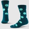 Product Shot: The Dotalicious Light Cushion Crew Socks by Woolx showcase two socks in teal, made from odor-resistant Merino wool, adorned with large light blue polka dots. One sock is positioned upright, while the other lies flat against a plain light gray background.