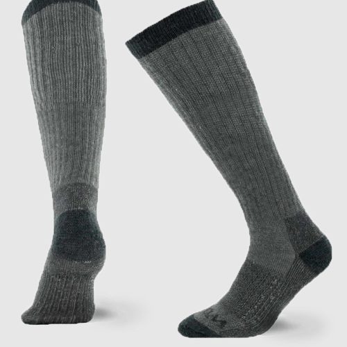 The product features the Extreme Full Cushion Over The Calf socks in Charcoal Heather from Woolx, depicted against a light background. One sock stands upright while the other is angled, highlighting its ribbed texture and cold-weather insulation.