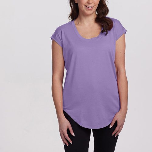 A woman with long brown hair, wearing the Woolx Gabi Tunic Top in Montana Grape and black pants, stands smiling against a plain white background. Her headband adds a charming touch as her hands are relaxed by her sides.