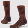 A pair of Joey Full Cushion Mid Calf Socks in Cinnamon Spice from Woolx stands upright on a light gray background, showcasing their textured, speckled brown and black design with ribbed detailing. The socks feature a cushioned sole with the brand name visible near the toe.