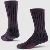 Against a light gray background, the Joey Full Cushion Mid Calf Socks in Warm Violet from Woolx stand upright, showcasing their dark purple hue with vertical black stripes. The word "wool" is displayed in pink lettering on the sole, highlighting their Merino wool composition. These women's socks are perfect for adding a touch of cozy warmth to any outfit.