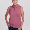 An older woman with short white hair smiles warmly, wearing a Rosie Sleeveless Polo from Woolx in Mesa Rose—a sleeveless pink shirt crafted from merino wool—and dark pants. Standing confidently against a plain white background, her left hand rests on her hip.