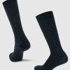 A pair of Woolx's Tilly Over The Calf Cable Knit Socks in black is displayed against a plain light gray background. One sock stands upright while the other is angled to highlight the intricate detailing on the heel and toe, making them ideal for all-season wear.