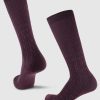 The Tilly Over The Calf Cable Knit Sock in Windsor Wine, by Woolx, is designed with warm Merino wool and features a delicate cable knit pattern. Against a light gray background, these socks are portrayed upright, gracefully displaying both side and front views.