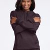 A person smiling and standing with crossed arms, dressed in a Woolx Avery Hoodie in Chocolate Plum and matching set. The dark-colored outfit perfectly complements the plain background, adding a subtle touch of style. | Keesha is 5'9.5", wearing a size S