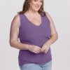 A woman with long brown hair smiles as she models the Woolx Vivi Ribbed Tank in Montana Grape, paired with light blue jeans. The sleeveless top features a stylish V-neckline and is part of her capsule wardrobe. She stands against a plain white background.