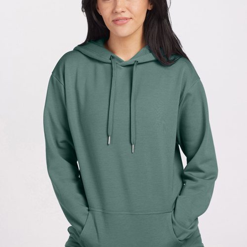 A person wearing an Avery Hoodie in Duck Green from Woolx stands against a neutral background, looking at the camera. Their dark hair falls loosely over their shoulders as their hands rest in the front pocket of the comfortable Merino wool garment. | Sarah is 5'8", wearing a size S