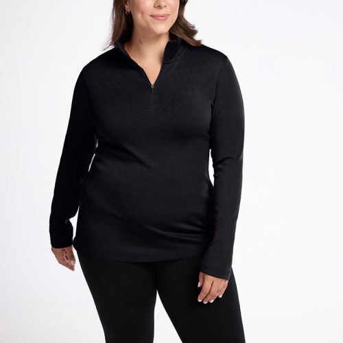 A person dressed in the Woolx Brooke 1/4 Zip OLD, a black top and pants, stands against a plain white background. The elegant athletic fit features moisture-wicking fabric and a zippered collar. They smile softly while looking to the side, showcasing the stylish design.