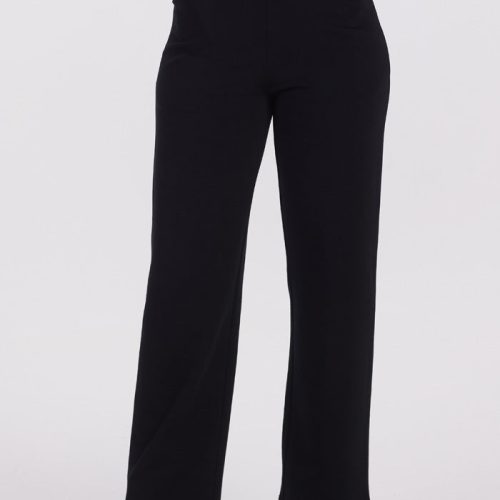 A person is showcasing the Woolx Ellie Wide Leg Pants in black, paired with a dark green long-sleeve top and accessorized with hands tucked comfortably into the pants' pockets. Their look is completed with black ankle boots, all set against a plain white background that highlights the sleek ensemble.