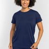 A person with curly hair is smiling and wearing the Billie Lounge Tee - Starry Night from Woolx, paired with matching pants. They are standing against a plain light gray background. | Tori is 5'7", wearing a size S