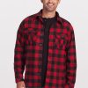 A man dressed in a Woolx Burlington Jacket in Red Black Plaid over a black top stands smiling against a plain background. He has short, gray hair and is wearing blue jeans. | Matthew is 6', wearing a size L