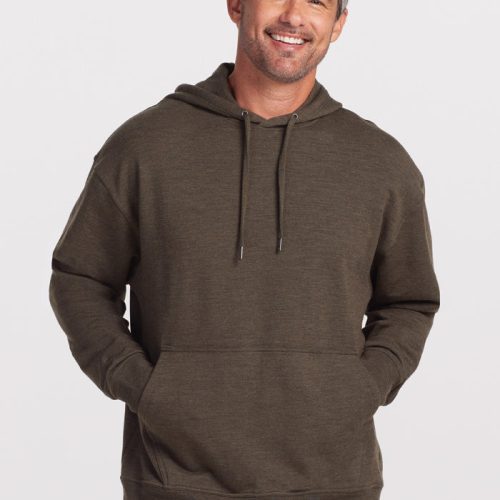 A man with short, graying hair and a beard is smiling and posing in the Woolx Chase Hoodie in Dark Moss. His hands are in the front pockets of the hoodie, and he is wearing blue jeans. The background is plain and light-colored. | Matthew is 6', wearing a size L