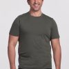 A smiling man in a Woolx Endurance Tee - Deep Fern stands with his hands relaxed by his sides. He has short brown hair and is wearing dark jeans. The background is a plain white. | Brandon is 6’3.5”, wearing a size XL