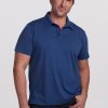 A man wearing a Woolx Preston Polo in Midnight Sky Stripe paired with dark jeans is standing against a plain light background, gently smiling with one hand in his pocket. | Brandon is 6’3.5”, wearing a size XL