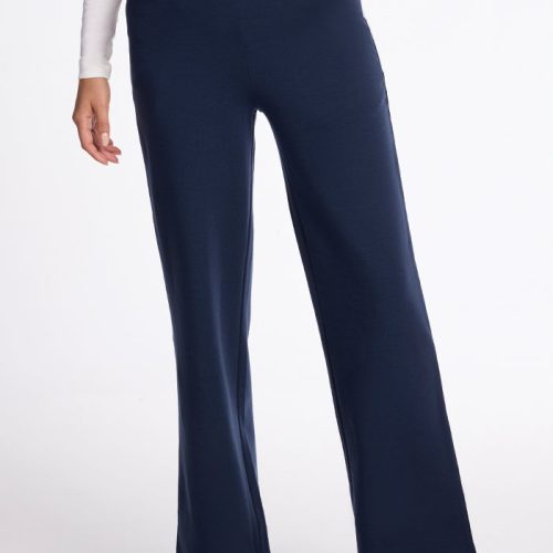 Someone is styled in a white long-sleeve top, paired with the Woolx Ellie Wide Leg Pants in Deep Navy and brown shoes. The striking wide-leg fit stands out against a plain white background, with only the lower half of the body visible. | Georgia is 5'10", wearing a size XS