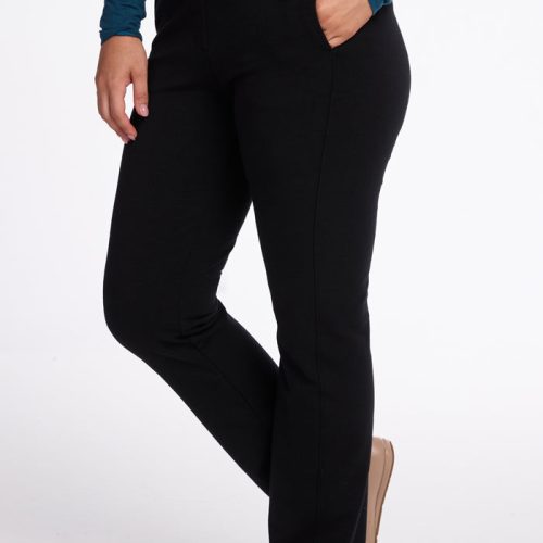 A person is wearing Woolx's Emerson Straight Leg Pants in black, paired with a long-sleeve teal top, their right hand casually resting in a pocket. With beige shoes completing the look, they exude comfort against the plain white background. | Sarah is 5'8", wearing a size S