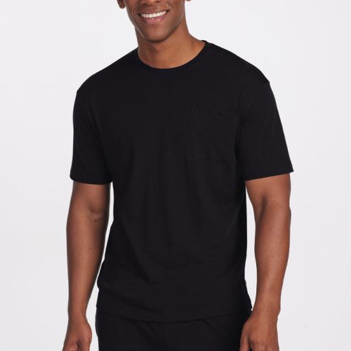 A person wearing the Finn Top in black by Woolx and matching pants is smiling, standing against a plain white background.