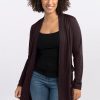 A person with curly hair smiles while wearing the Woolx Paisley Cardigan in French Roast, crafted from an Australian Merino Wool blend, over a black top and blue jeans, standing against a plain white background. | Tori is 5'7", wearing a size S