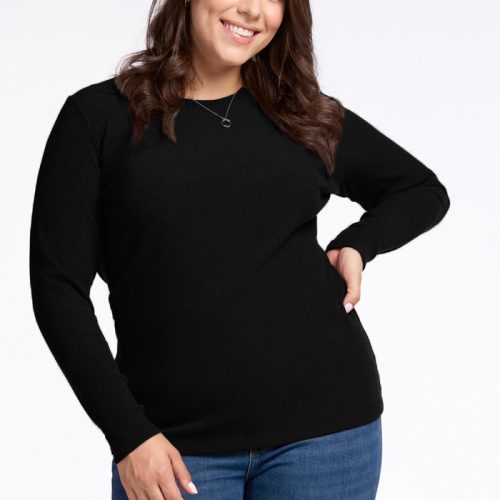 A person with long brown hair smiles at the camera, wearing the Woolx Hadley Ribbed Crew in black and blue jeans. They have one hand on their hip and the other arm relaxed by their side, exuding a luxurious feel against the plain white background. | Juliana is 5'10", wearing a size XL