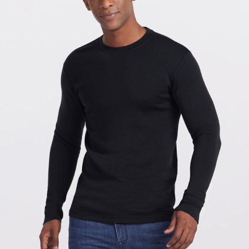 A person wearing a fitted Glacier Long Sleeve Crew OLD by Woolx in black and blue jeans stands against a plain white background, looking at the camera with a slight smile and hands relaxed by their sides. | Trell is 6’2”, wearing a size M