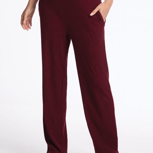 A person wearing Woolx's Luca Ribbed Pants in Cranberry Melange with their left hand in a pocket. The pants feature a relaxed, wide-leg fit and are paired with white sneakers against a plain white background. | Georgia is 5'10", wearing a size XS