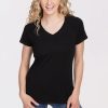 A person with long curly hair is smiling while wearing a black Mia V Neck OLD T-shirt from Woolx and blue jeans, standing against a plain white background. | Jordan is 5’6”, wearing a size S