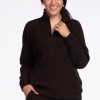 A person wearing the Woolx Quinn Ribbed 1/4 Zip in French Roast stands against a white background. They are smiling and have one hand in their pocket, showcasing the ideal travel outfit. | Sarah is 5'8", wearing a size S