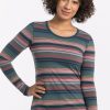 A person with curly hair smiles while wearing the Woolx Remi Long Sleeve T-Shirt in Adirondack 2.0 Stripe, made of lightweight fabric. Their hand rests on their hip against the plain white background. | Tori is 5'7", wearing a size S