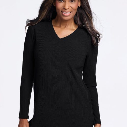 A person with long hair smiles while wearing the Evie Tunic - Black from Woolx. The temperature-regulating Merino wool fabric ensures comfort, accentuated by the plain white background. | Keesha is 5’9.5”, wearing a size S