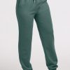 A person dressed in Woolx's Parker Sweatpants in Duck Green stands barefoot on a white surface. These moisture-wicking sweatpants come equipped with an adjustable drawstring and elastic cuffs at the ankles, providing comfort while effectively managing odors. | Tori is 5'7", wearing a size S