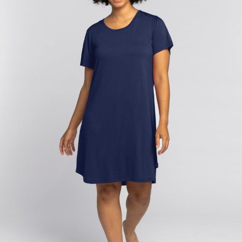 A person with curly hair is wearing a navy blue short-sleeved Desi Nightgown - Starry Night from Woolx and is walking barefoot. The background is a plain light gray.