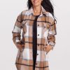 A woman smiling, wearing the Woolx Sutton Shacket in a Camel Plaid pattern. Made from premium merino wool in a regular fit, her hands rest in the pockets, complementing her long black hair against the plain white background.