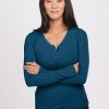 A person with long dark hair stands against a plain background, wearing the Reese Ribbed Henley in Real Teal from Woolx. They are smiling with arms crossed. | Mary is 5'8", wearing a size S