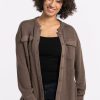 A person with curly hair smiles while wearing the Oaklynn Waffle Shacket in Latte from Woolx over a black top and jeans. The background is plain white. | Tori is 5'7", wearing a size S