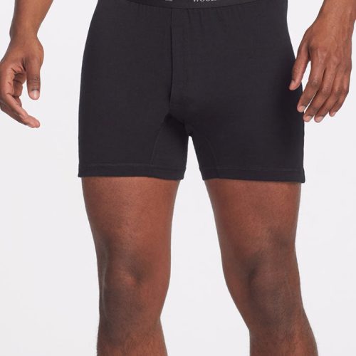 A person is wearing black Breathe Boxer Shorts OLD with a black waistband, featuring the Woolx brand in white lettering. These lightweight Merino boxer shorts are renowned for their breathability, set against a plain white background.