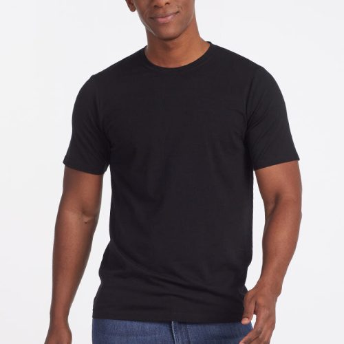 A person wearing a plain black Woolx Endurance Tee OLD and blue jeans stands against a white background, looking at the camera with a slight smile.