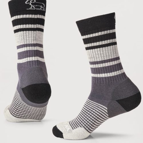 The Everyday Light Cushion Crew Socks from Woolx, available as a stocking stuffer final sale deal, come in a stormy stripe color with a small white sheep design on top. These durable socks are crafted from odor-resistant merino wool and include ribbed cuffs, a reinforced heel and toe, and various stripe patterns throughout the body, all set against a plain background.