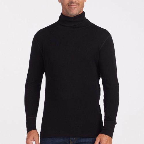 A person with short hair and light stubble is wearing a Woolx Prescott Turtleneck in black, made from soft Merino wool, along with blue jeans. They are standing against a plain white background and looking at the camera with a slight smile. | Lee is 6', wearing a size L