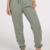 A person stands barefoot against a plain background, wearing mint Parker Sweatpants by Woolx. One hand rests in a pocket, and the Merino wool pants feature an elastic waistband with a drawstring and cuffed ankles, offering temperature-regulating comfort.