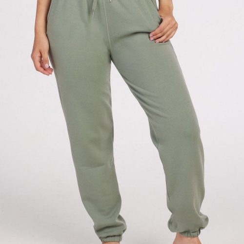 A person stands barefoot against a plain background, wearing mint Parker Sweatpants by Woolx. One hand rests in a pocket, and the Merino wool pants feature an elastic waistband with a drawstring and cuffed ankles, offering temperature-regulating comfort.