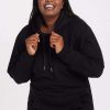 A person smiling and wearing the cozy Avery Hoodie - Black from Woolx, holding the drawstrings with both hands, enjoying the soft touch of merino wool. | Le'Quita is 5'11", wearing a size XL