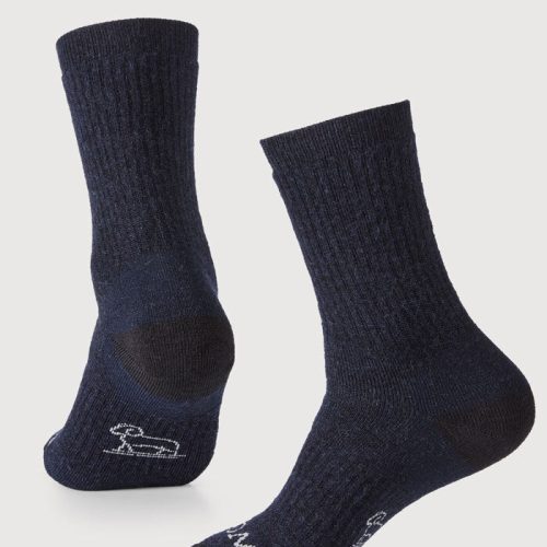 A pair of Woolx's Core Crew Sock Full Cushion in navy, crafted from moisture-wicking Merino fabric, is displayed against a light background. The socks feature white logos on the soles and are shown from various angles to emphasize their texture and design.