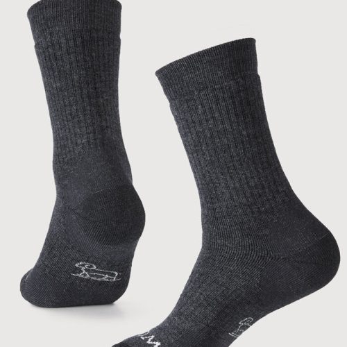 A pair of Milo Full Cushion Cold Weather Socks in dark grey charcoal, by Woolx, is set against a plain white background. Made from moisture-wicking Merino wool, one sock stands upright while the other shows its foot forward, both showcasing a slightly textured design.